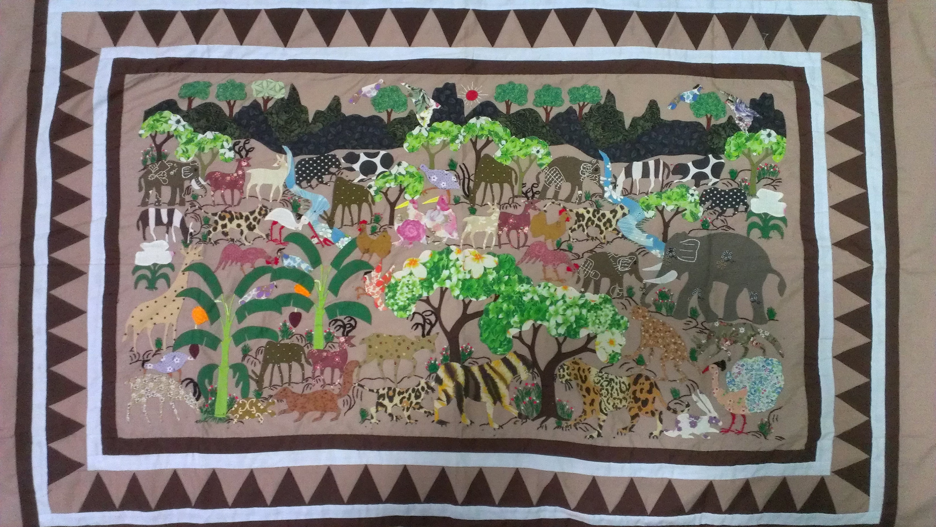 paj ntaub - hand embroidered story cloth with animals and trees and mountains in the background
