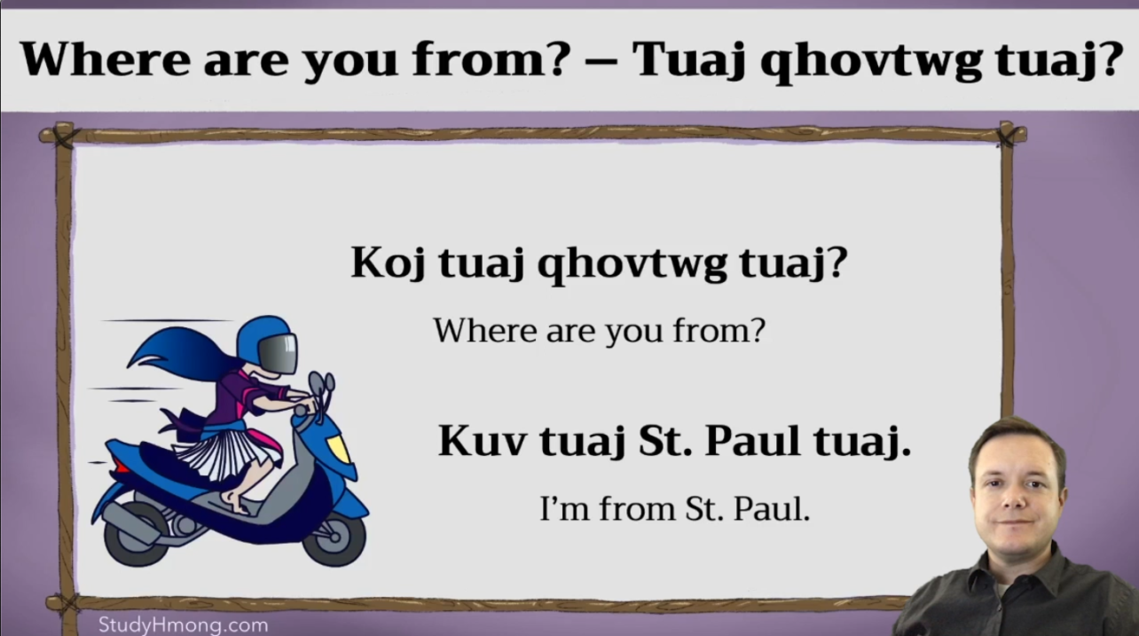 A Hmong language lesson slide with the phrase “Where are you from?” and its translation, plus a scooter illustration and a presenter in the corner.